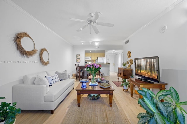 living room featuring ornamental molding, light wood-type flooring, and ceiling fan