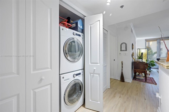 clothes washing area featuring stacked washing maching and dryer, light hardwood / wood-style floors, and ornamental molding