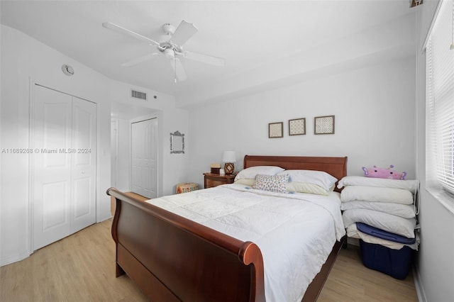 bedroom featuring ceiling fan, light wood-type flooring, and two closets