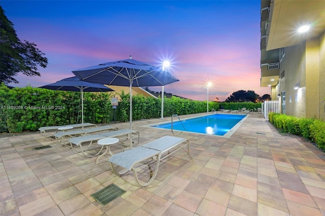 pool at dusk with a patio area