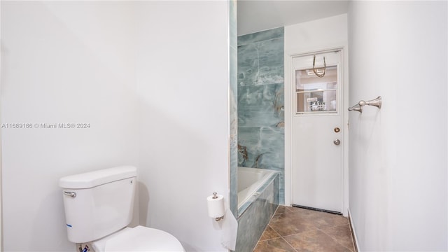 bathroom with a washtub, tile patterned flooring, and toilet