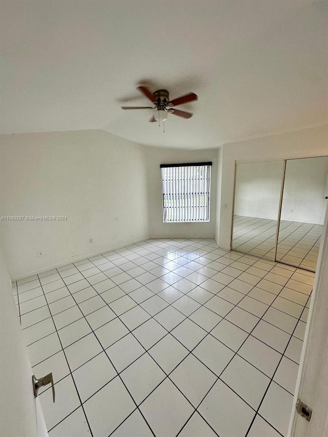 empty room with lofted ceiling, light tile patterned flooring, and ceiling fan