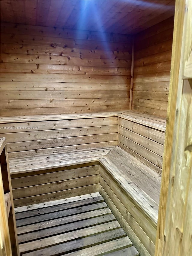 view of sauna with wooden ceiling and wooden walls