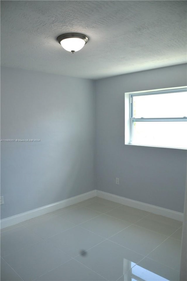 tiled spare room with a textured ceiling