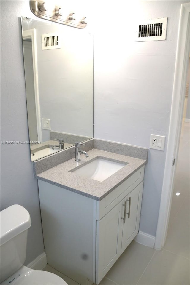 bathroom with tile patterned flooring, vanity, and toilet