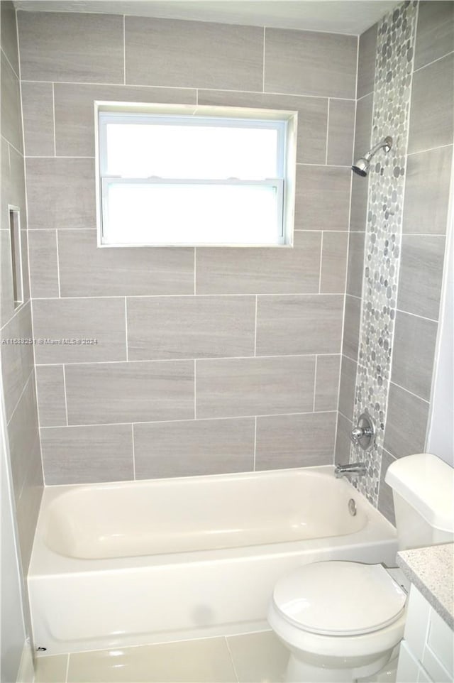 full bathroom with a wealth of natural light, vanity, toilet, and tiled shower / bath combo