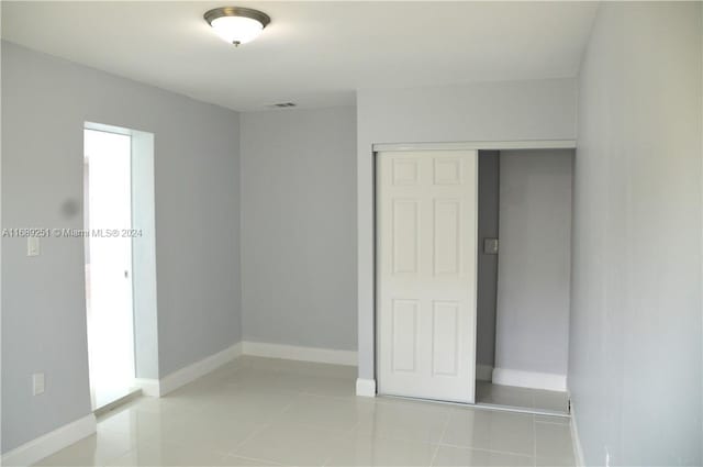 unfurnished bedroom with light tile patterned flooring and a closet