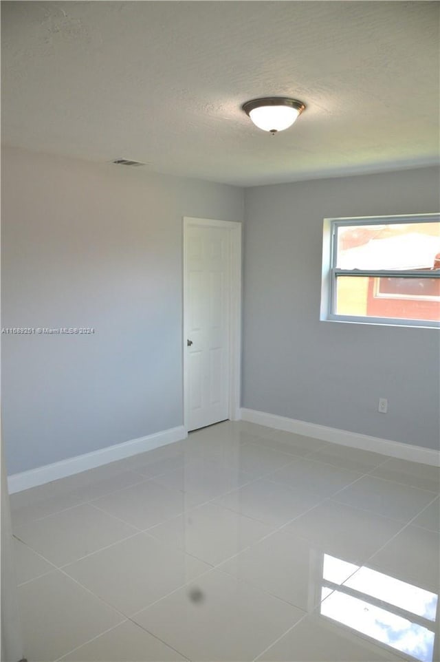 tiled spare room with a textured ceiling