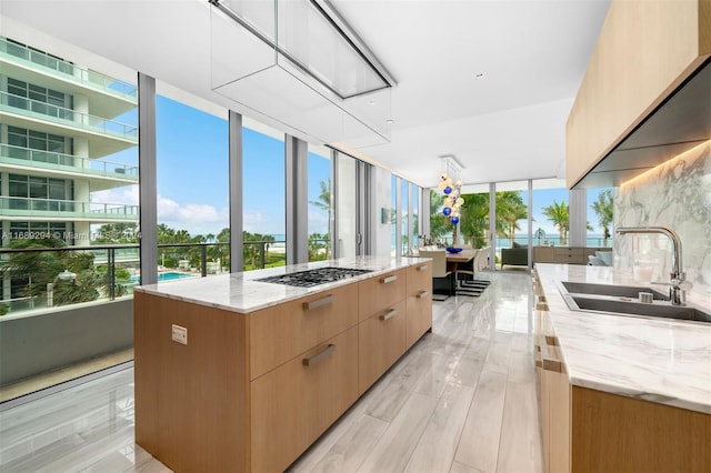 kitchen featuring sink, light hardwood / wood-style floors, a kitchen island, and light stone counters