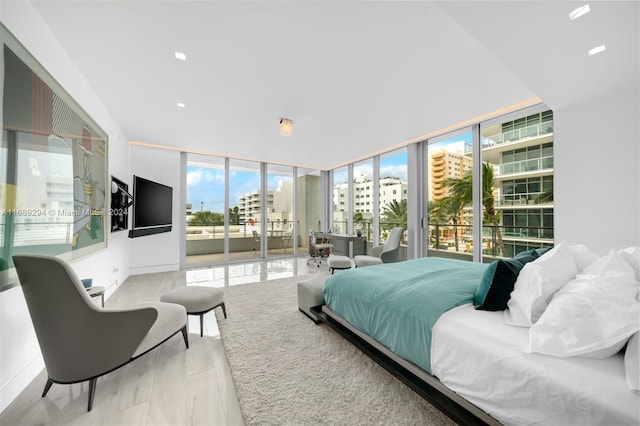 bedroom featuring light hardwood / wood-style floors, a wall of windows, and access to outside