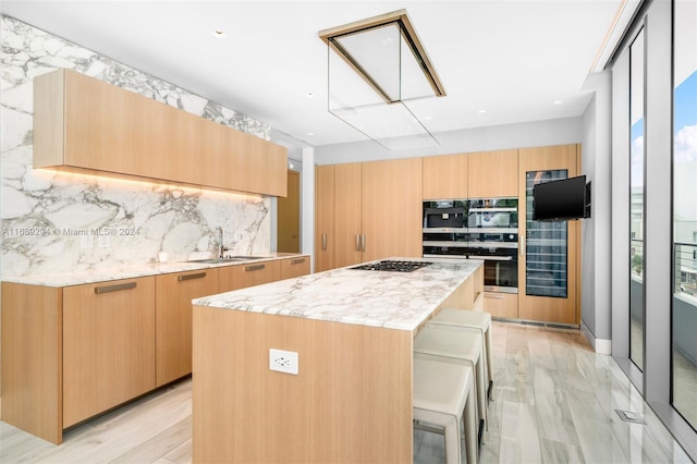 kitchen featuring a kitchen breakfast bar, light wood-type flooring, tasteful backsplash, stainless steel gas cooktop, and a center island