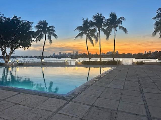 pool at dusk featuring a patio area