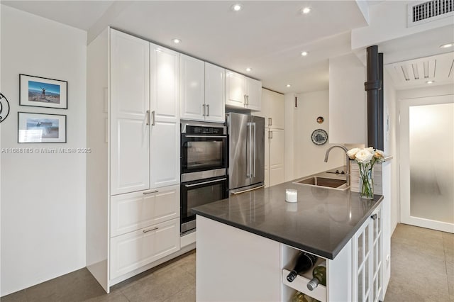 kitchen featuring sink, light tile patterned floors, kitchen peninsula, white cabinets, and appliances with stainless steel finishes