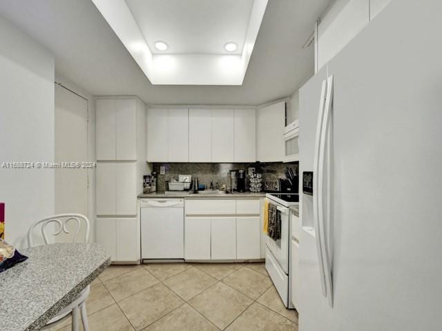 kitchen featuring white cabinetry, decorative backsplash, light tile patterned floors, and white appliances