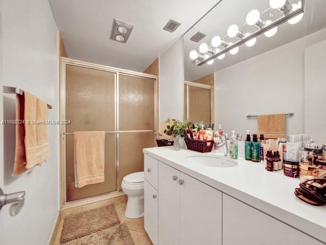 bathroom with toilet, vanity, tile patterned floors, and a shower with door