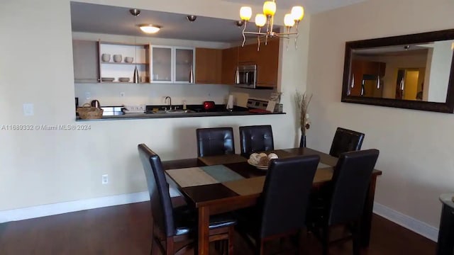 dining area with dark wood-type flooring, sink, and a notable chandelier