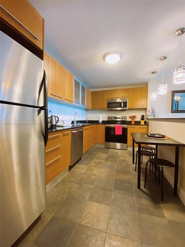 kitchen with sink, decorative light fixtures, and appliances with stainless steel finishes