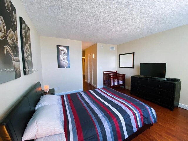 bedroom with a textured ceiling and dark hardwood / wood-style floors