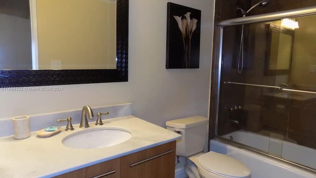 full bathroom featuring toilet, vanity, and enclosed tub / shower combo