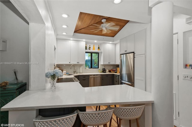 kitchen with white cabinetry, kitchen peninsula, appliances with stainless steel finishes, and a kitchen bar