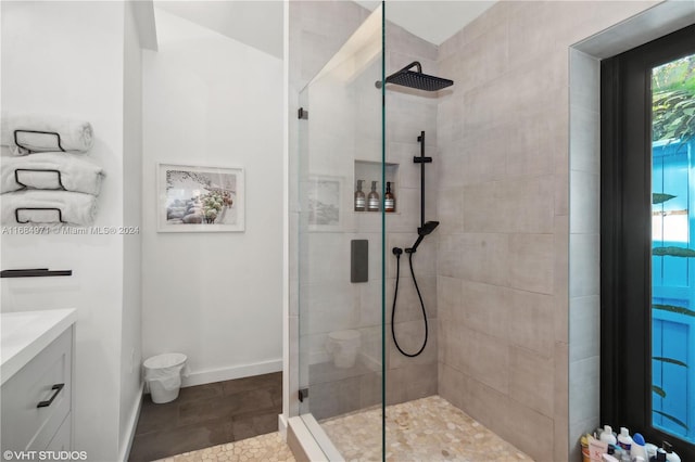 bathroom featuring tile patterned flooring, vanity, and a tile shower