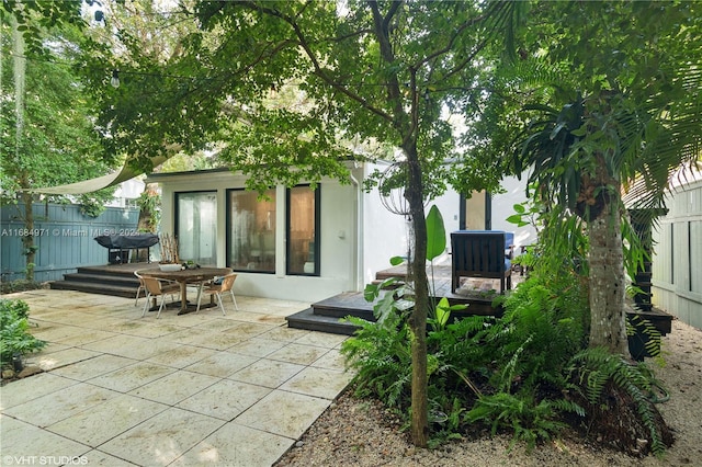 rear view of house with an outdoor structure, a wooden deck, and a patio