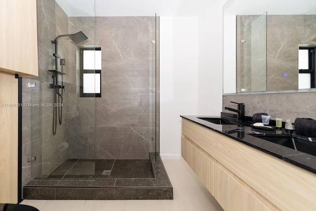 bathroom featuring tile patterned flooring, vanity, a tile shower, and backsplash