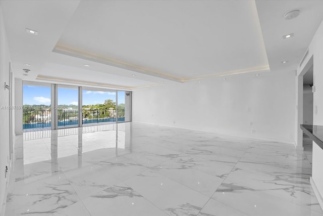 unfurnished room featuring floor to ceiling windows and a tray ceiling