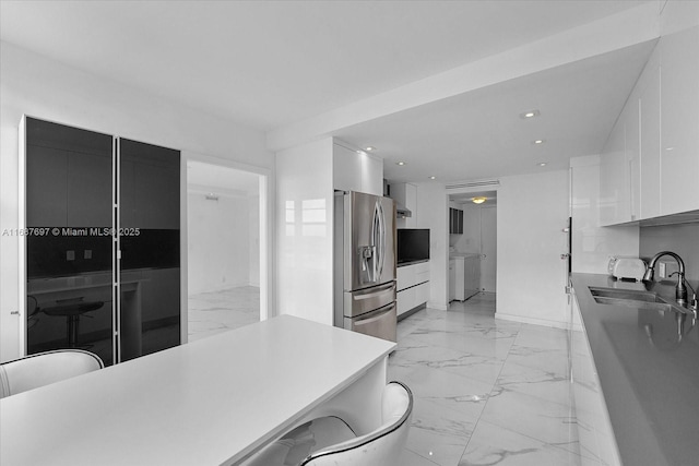 kitchen featuring stainless steel refrigerator with ice dispenser, sink, white cabinets, and a breakfast bar area