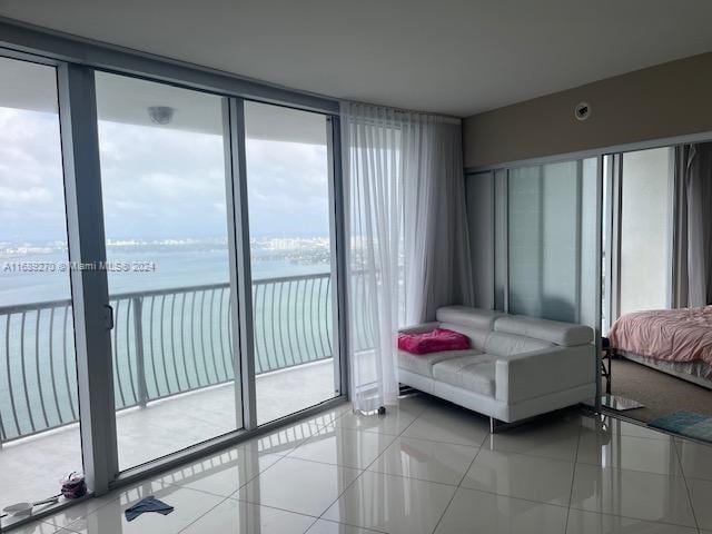 tiled bedroom featuring access to exterior, a water view, and multiple windows