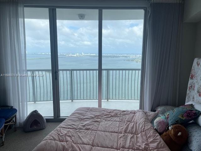 carpeted bedroom featuring multiple windows and a water view