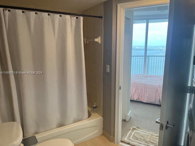 bathroom featuring toilet, a water view, and shower / bath combination with curtain