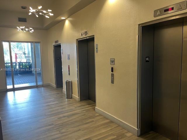 interior space with a high ceiling, elevator, and wood-type flooring