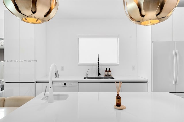 kitchen with white refrigerator, sink, and white cabinets