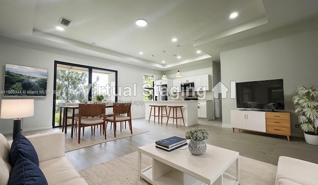 living room featuring light hardwood / wood-style floors and a tray ceiling