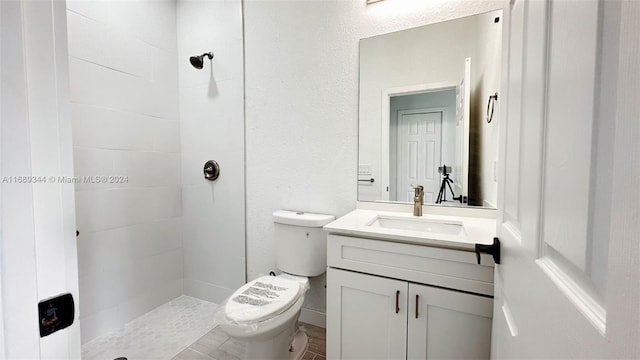 bathroom featuring a tile shower, vanity, and toilet