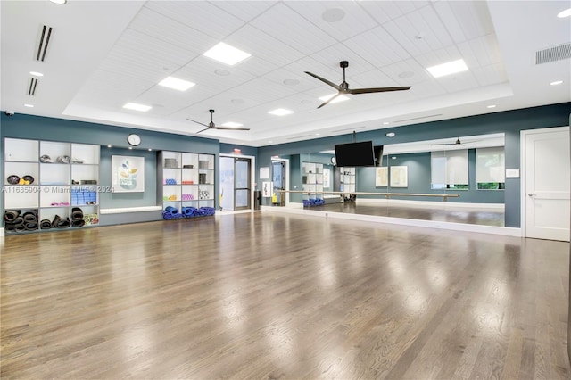 workout room with wood-type flooring and a raised ceiling