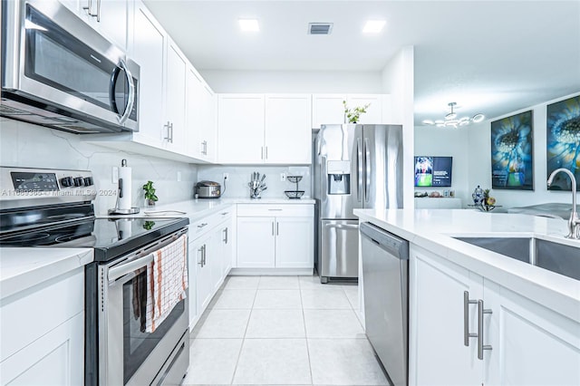 kitchen with decorative backsplash, appliances with stainless steel finishes, sink, light tile patterned floors, and white cabinets