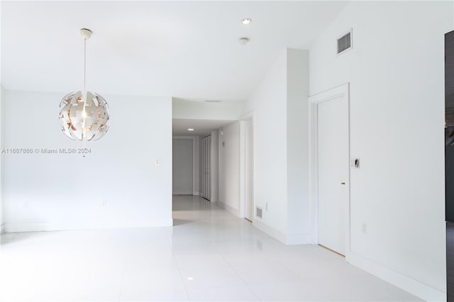 hallway with a notable chandelier and light tile patterned floors