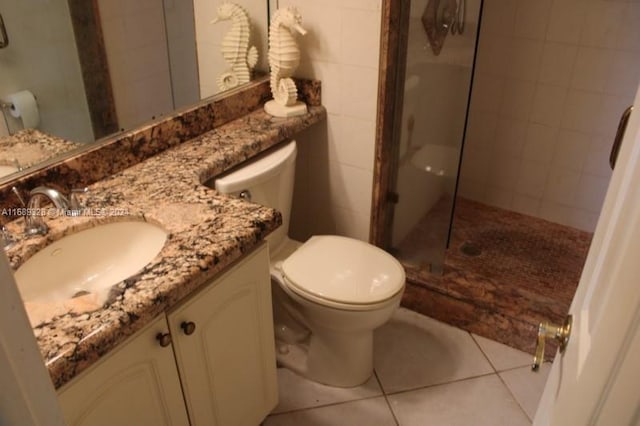 bathroom with tile patterned flooring, vanity, toilet, and a shower with door