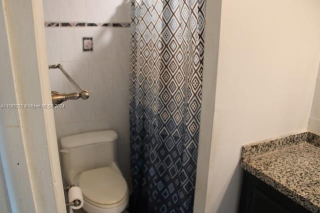 bathroom with tile walls, vanity, toilet, and a shower with curtain