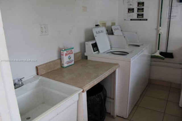 washroom with washing machine and clothes dryer, light tile patterned flooring, and sink