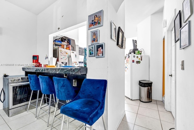 interior space with light tile patterned floors, white refrigerator, and stainless steel fridge