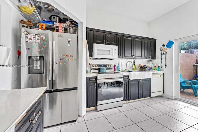 kitchen featuring sink, light tile patterned floors, light stone counters, and appliances with stainless steel finishes