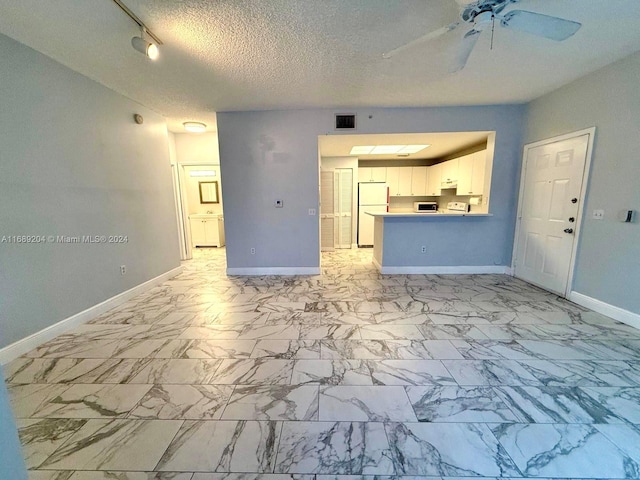 unfurnished living room featuring ceiling fan, a textured ceiling, and track lighting