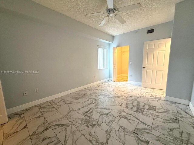 empty room with ceiling fan and a textured ceiling