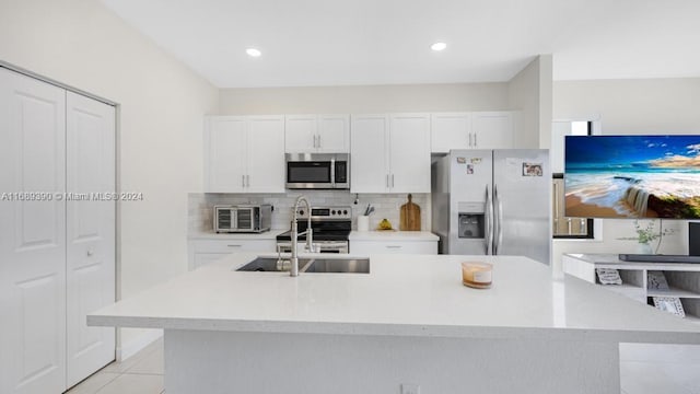 kitchen with white cabinets, sink, light tile patterned floors, an island with sink, and appliances with stainless steel finishes