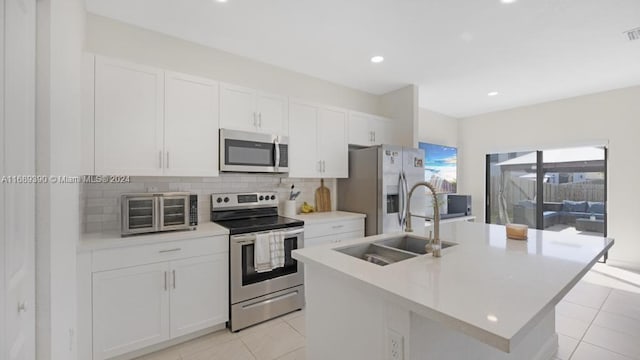 kitchen with stainless steel appliances, a center island with sink, and sink