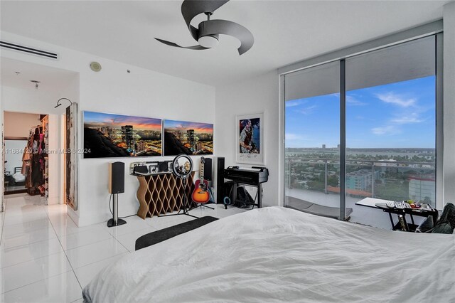 tiled bedroom with expansive windows, ceiling fan, and access to exterior