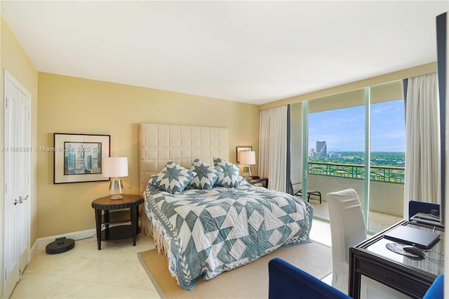 tiled bedroom featuring a view of city, access to outside, and baseboards